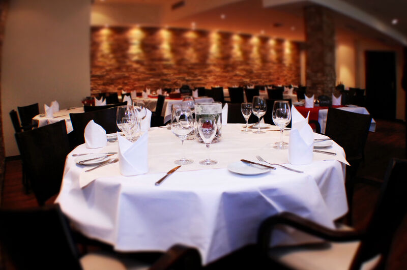 Festsaal mit festlich eingedecktem rundem Tisch, Steinwand mit Spotlights